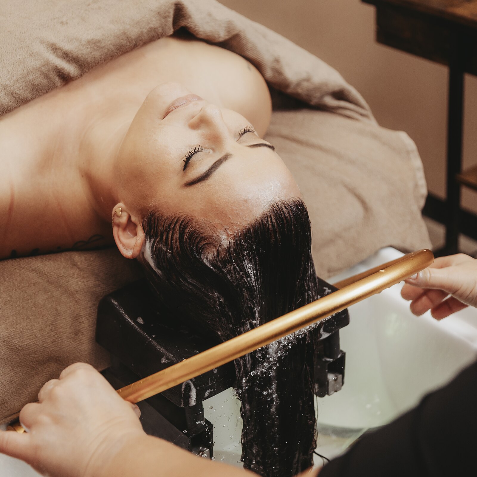 Cliënt ontspant tijdens de Japanese Head Spa onder de gouden waterring bij Medische Haarstudio Nauta in Veendam